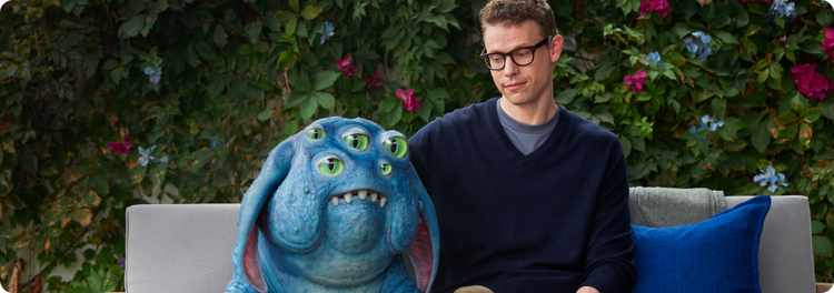 Creature and man sitting next to one another on a couch