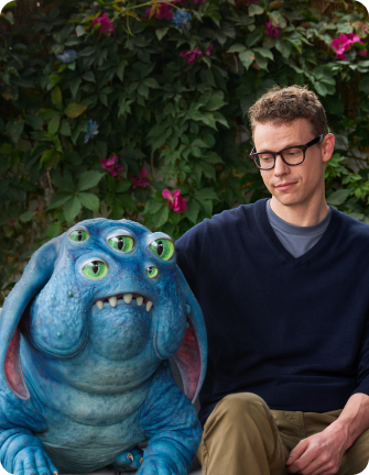 Creature and man sitting next to one another on a couch