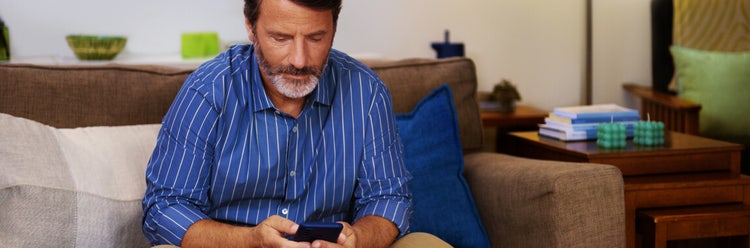 A man on his phone sitting on a couch