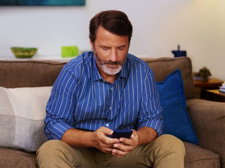 A man on his phone sitting on a couch